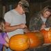 2 adults and a child carving pumpkins for the Pumpkin Hike